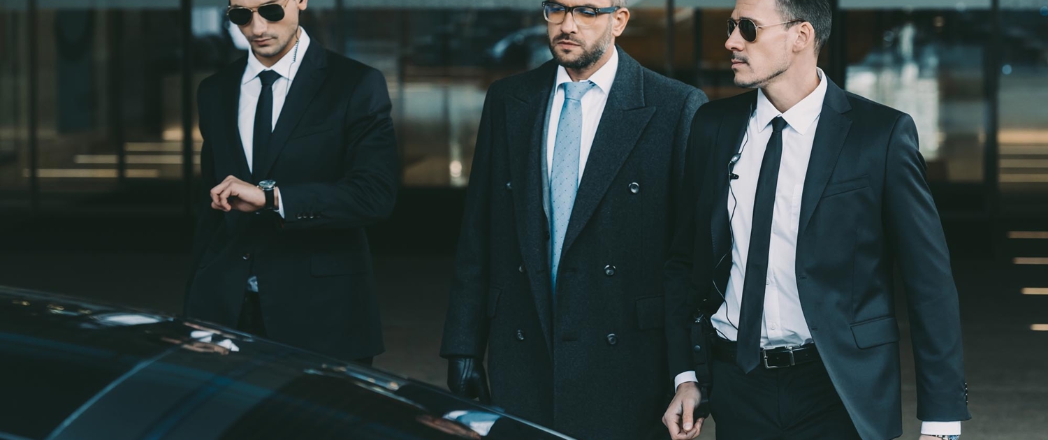 Front view of two executive protection specialists leading a client to his car