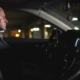 Side view of a man sitting in a dark car