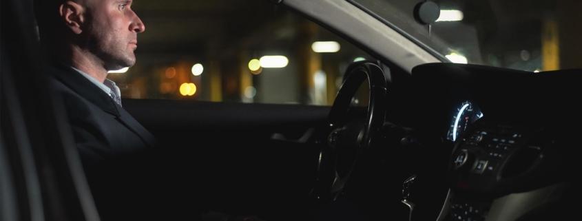 Side view of a man sitting in a dark car
