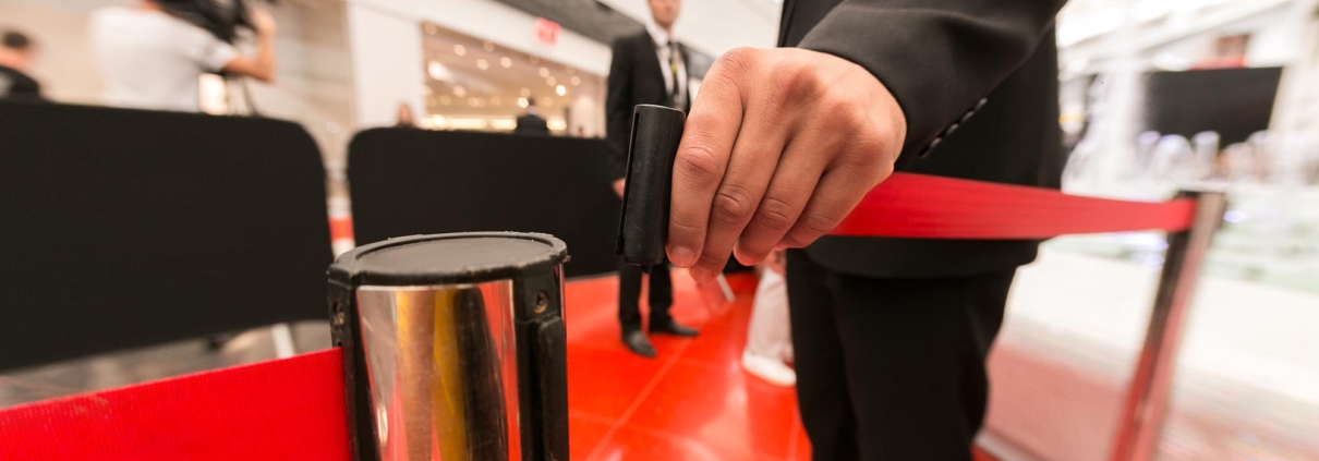 Side view of a member of security personnel closing the gate at a red carpet event