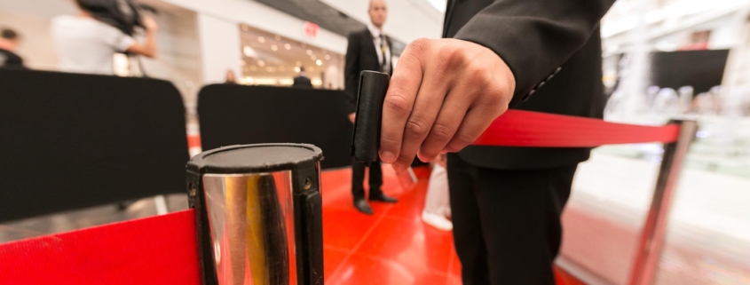 Side view of a member of security personnel closing the gate at a red carpet event