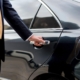 Side view of a person putting their hand on a car door handle