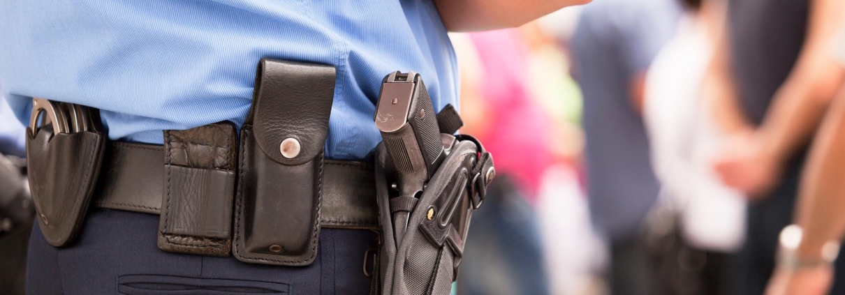 Side view of a police officer standing with a gun holstered to their hip