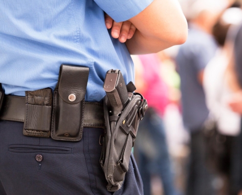 Side view of a police officer standing with a gun holstered to their hip