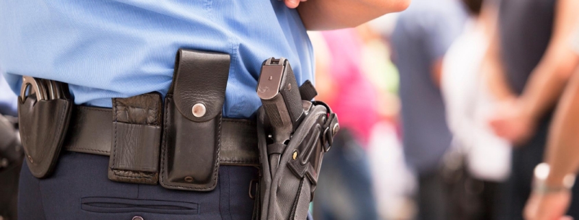 Side view of a police officer standing with a gun holstered to their hip