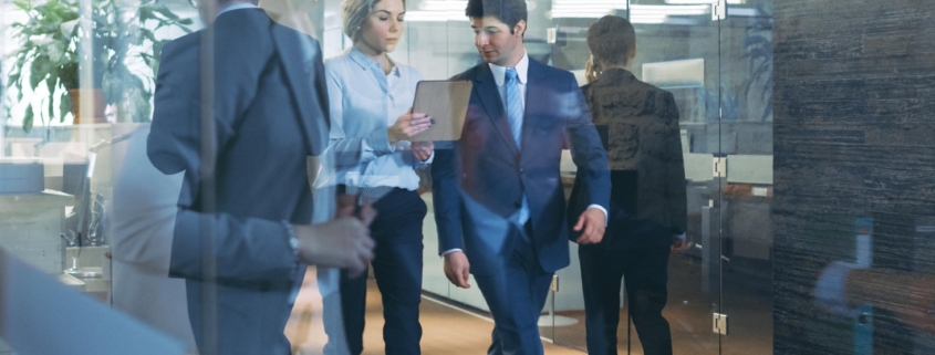 Side view of two businesspeople walking down a hallway