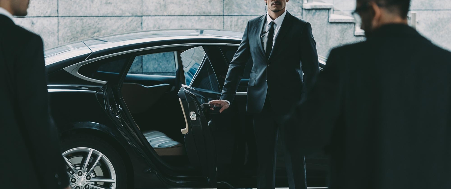 Front view of an executive protection officer opening a car door