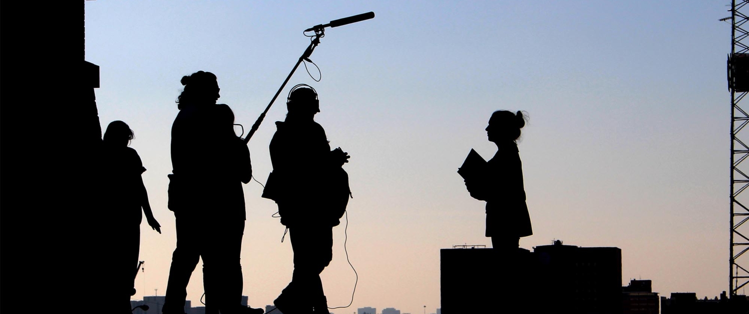 Silhouettes of people working on a film set