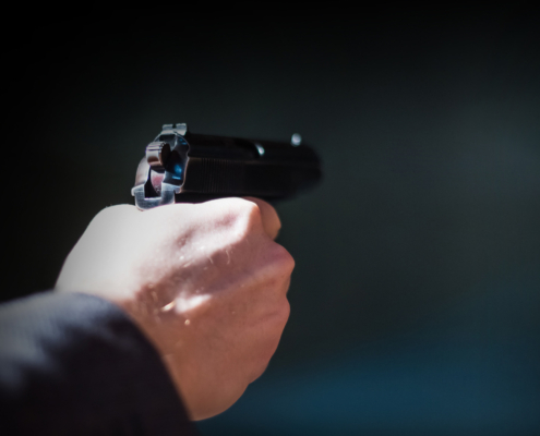 A man shoots a pistol. Shallow depth of field. Close-up.