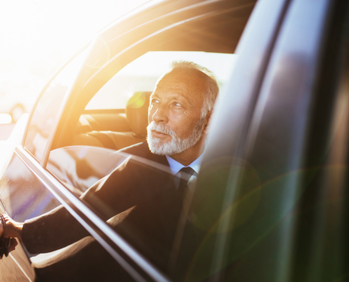Senior business man sitting in his limousine. Business concept. Back light.