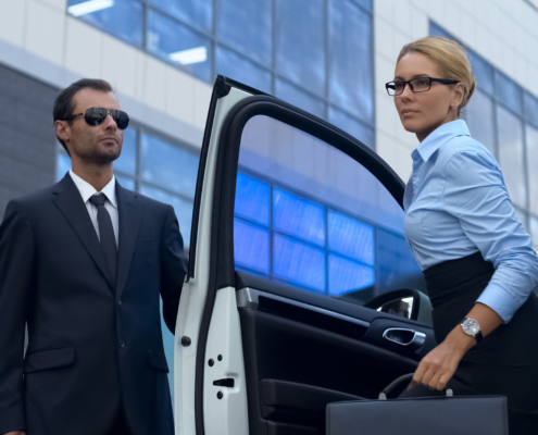 Bodyguard in suit opening car door to female boss