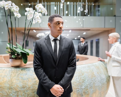 security man looking away near blurred businesswoman at hotel reception