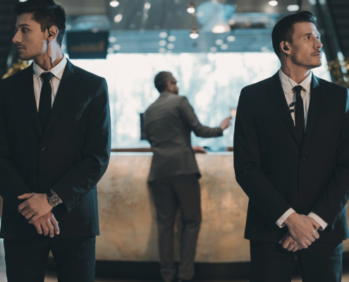two bodyguards waiting for businessman standing at reception counter