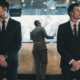 two bodyguards waiting for businessman standing at reception counter